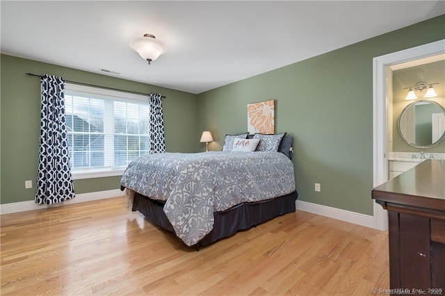 bedroom with light hardwood / wood-style floors and ensuite bath