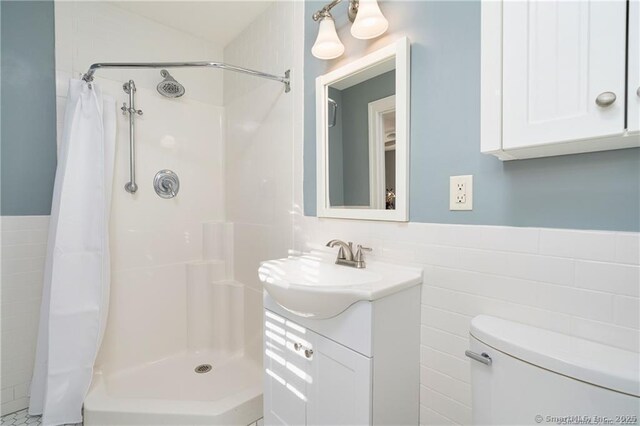 bathroom featuring toilet, tile walls, vanity, and curtained shower