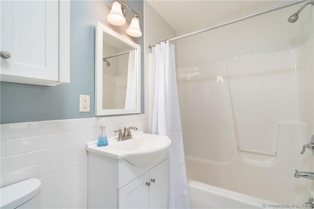 full bathroom featuring tile walls, toilet, vanity, and shower / bathtub combination with curtain