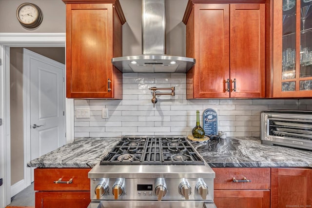 kitchen with backsplash, stone counters, wall chimney exhaust hood, and stove