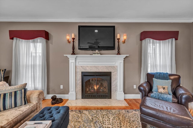 living room featuring a healthy amount of sunlight, a premium fireplace, crown molding, and hardwood / wood-style floors