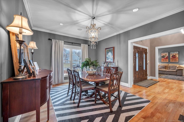 dining area with hardwood / wood-style flooring, crown molding, and a chandelier