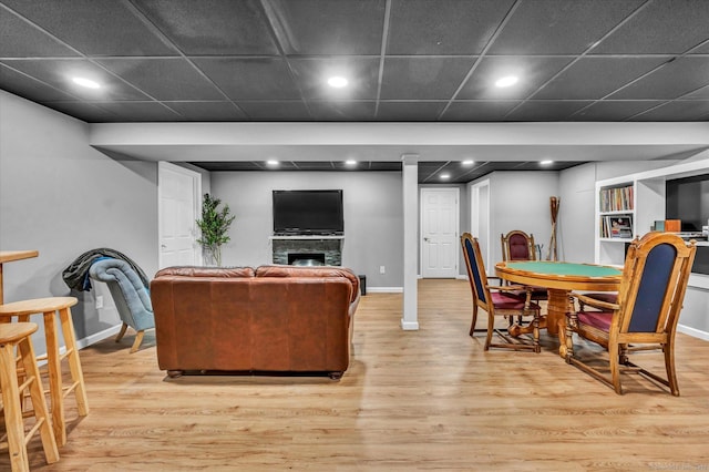 living room featuring a paneled ceiling, light wood-type flooring, and a fireplace