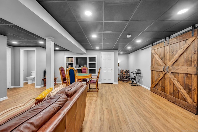 living room featuring a paneled ceiling, a barn door, and hardwood / wood-style floors