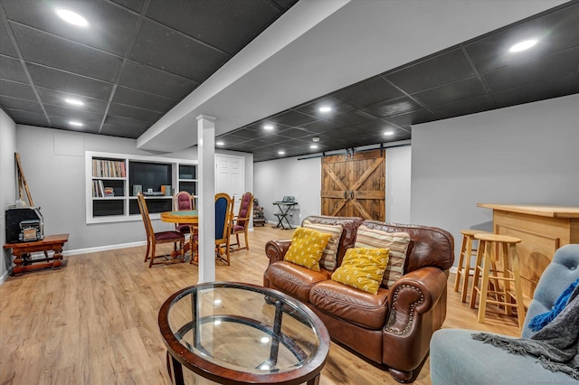 living room featuring hardwood / wood-style flooring, a paneled ceiling, and a barn door