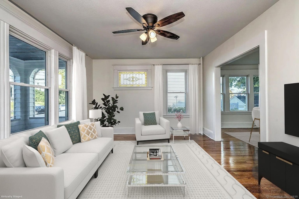 living room featuring dark wood-type flooring, a textured ceiling, ceiling fan, and a wealth of natural light