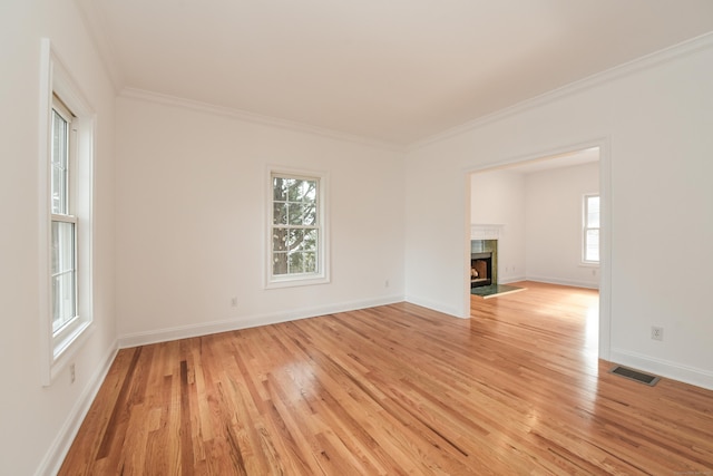 unfurnished living room featuring a fireplace, ornamental molding, and light wood-type flooring