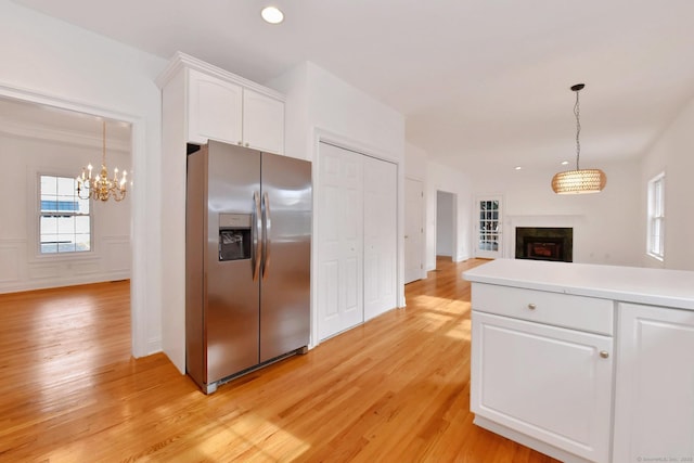 kitchen with white cabinetry, pendant lighting, stainless steel fridge, and light wood-type flooring