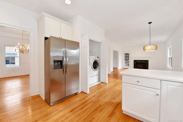 kitchen featuring pendant lighting, white cabinetry, washer / dryer, stainless steel refrigerator with ice dispenser, and light hardwood / wood-style flooring