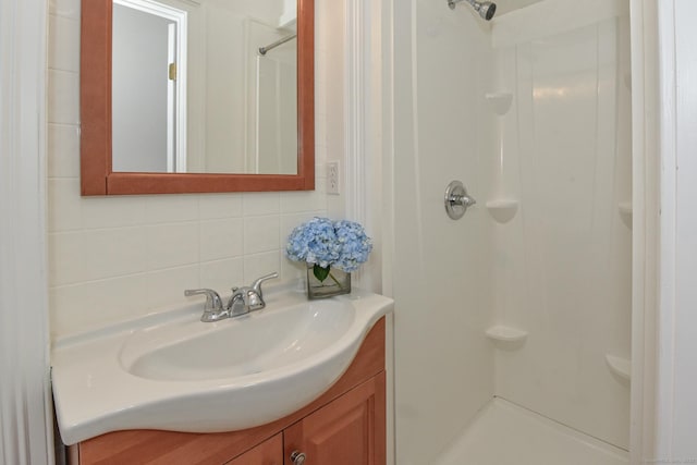 bathroom featuring tasteful backsplash, a shower, and vanity