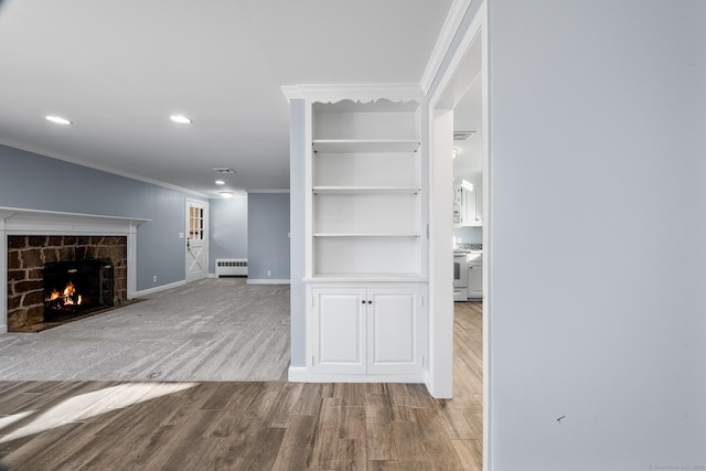 unfurnished living room featuring radiator, light wood-type flooring, built in shelves, and crown molding