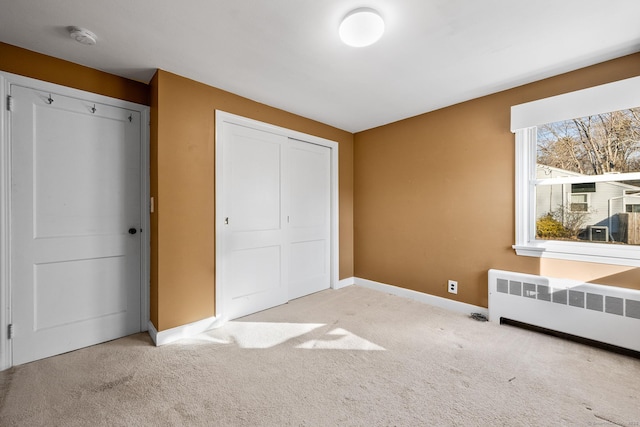 unfurnished bedroom with a closet, radiator heating unit, and light carpet