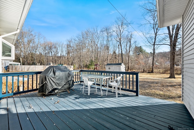 wooden terrace featuring area for grilling and a shed