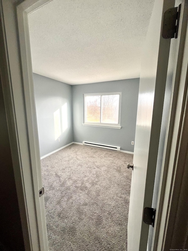 carpeted spare room with a textured ceiling and baseboard heating