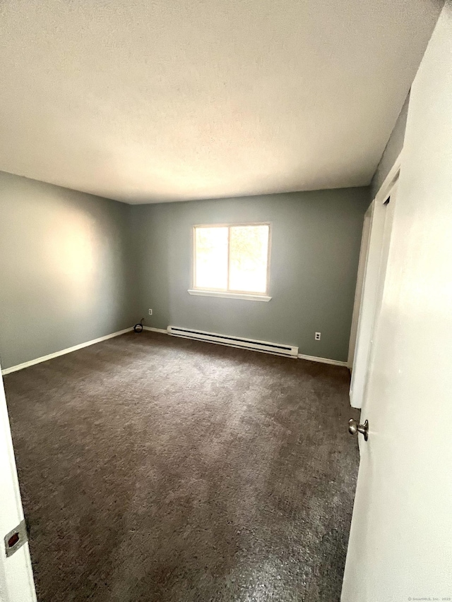 spare room with a textured ceiling, baseboard heating, and dark colored carpet