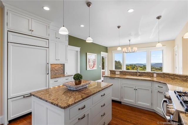 kitchen with a center island, high quality appliances, backsplash, and decorative light fixtures