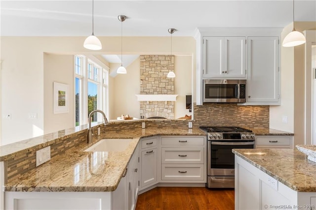 kitchen with tasteful backsplash, appliances with stainless steel finishes, sink, and hanging light fixtures