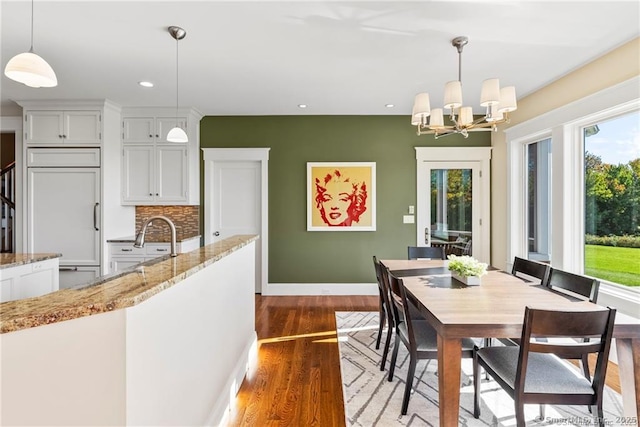 dining area featuring wood-type flooring, sink, and an inviting chandelier