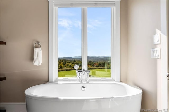 bathroom with a tub, plenty of natural light, and a mountain view