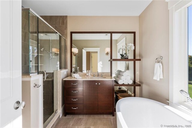 bathroom with a wealth of natural light, tile patterned floors, vanity, and plus walk in shower