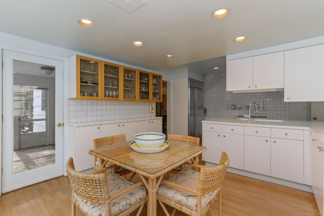 kitchen with tasteful backsplash, sink, light hardwood / wood-style flooring, and white cabinets