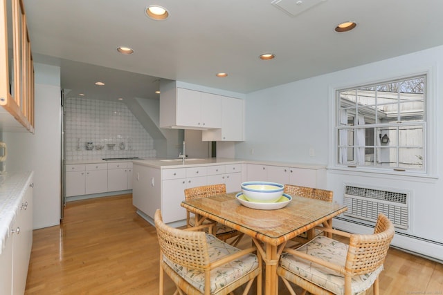 dining area with sink, a wall unit AC, and light wood-type flooring