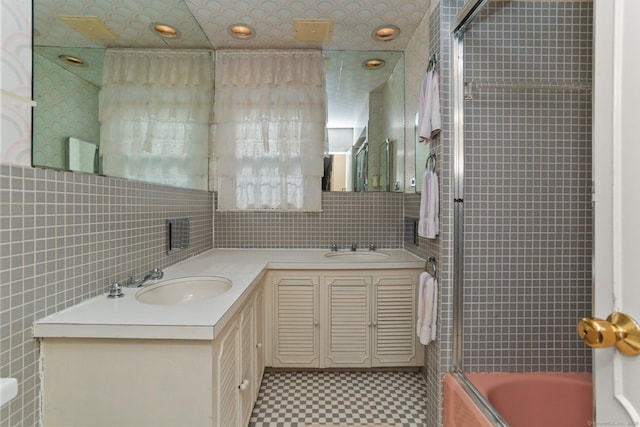 bathroom featuring vanity, shower / bath combination with glass door, and tile walls