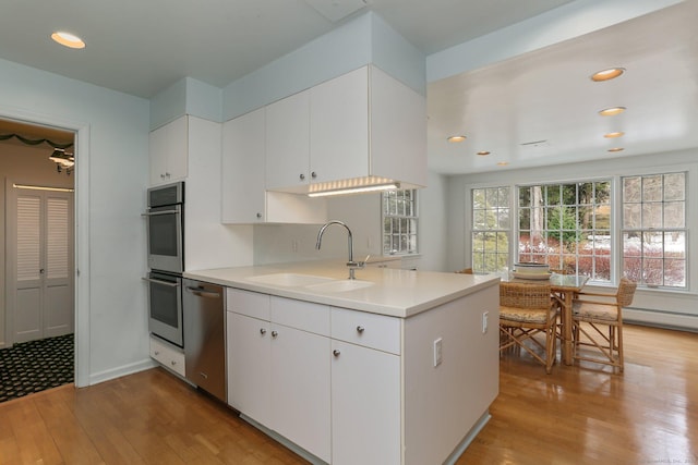 kitchen with white cabinetry, stainless steel appliances, sink, and light hardwood / wood-style flooring