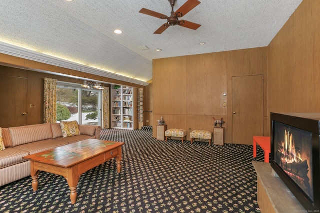 carpeted living room with ceiling fan, lofted ceiling, wooden walls, and a textured ceiling