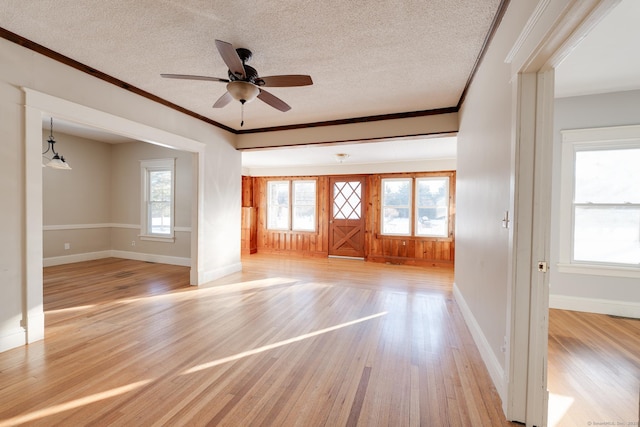 unfurnished living room featuring crown molding, ceiling fan, light hardwood / wood-style floors, and a textured ceiling