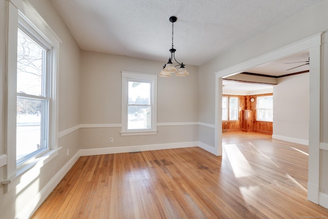 spare room featuring a chandelier, a textured ceiling, and light wood-type flooring