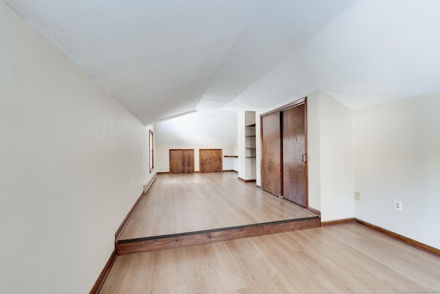 bonus room featuring built in shelves, lofted ceiling, and light hardwood / wood-style flooring