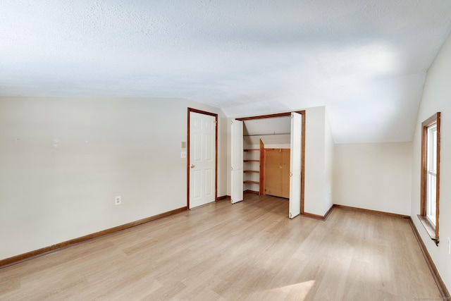 interior space featuring lofted ceiling, light hardwood / wood-style flooring, and a textured ceiling