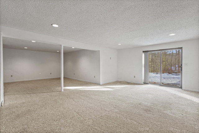 spare room featuring light colored carpet and a textured ceiling