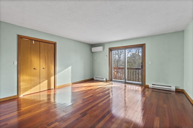 spare room with hardwood / wood-style floors, a baseboard heating unit, a wall mounted air conditioner, and a textured ceiling