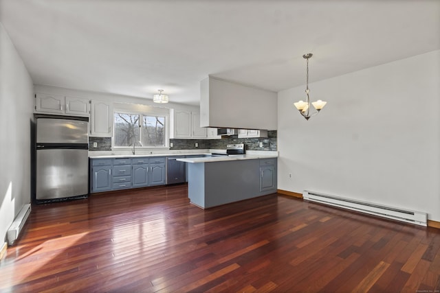 kitchen with pendant lighting, appliances with stainless steel finishes, an inviting chandelier, a baseboard heating unit, and kitchen peninsula