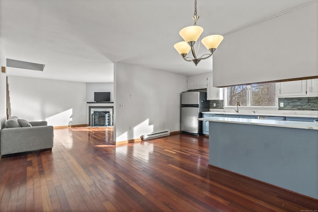 kitchen with white cabinetry, stainless steel refrigerator, baseboard heating, pendant lighting, and backsplash