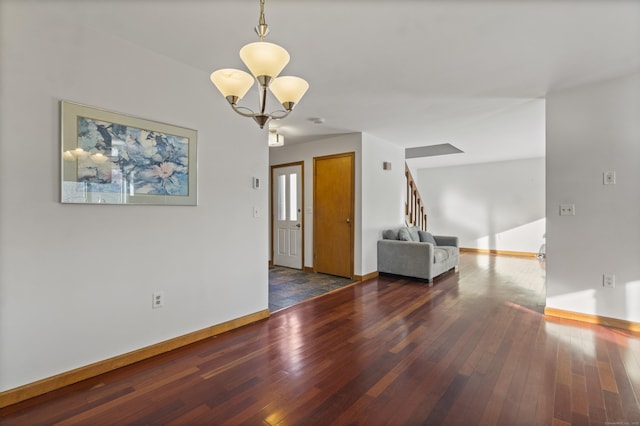 empty room with dark hardwood / wood-style floors and a notable chandelier