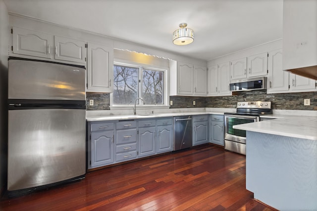 kitchen featuring appliances with stainless steel finishes, dark hardwood / wood-style floors, sink, and white cabinets