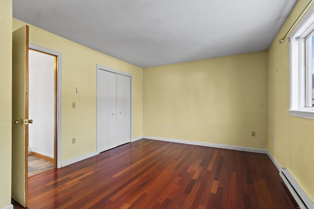 unfurnished bedroom featuring multiple windows, dark hardwood / wood-style floors, and baseboard heating