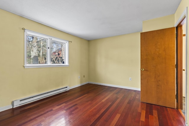 spare room with dark hardwood / wood-style floors and a baseboard heating unit