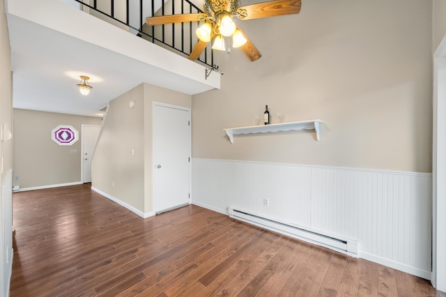 spare room with dark wood-type flooring, ceiling fan, and a baseboard radiator