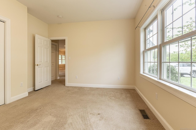 spare room with light colored carpet, baseboards, and visible vents