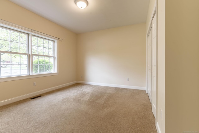unfurnished room with baseboards, visible vents, and light colored carpet