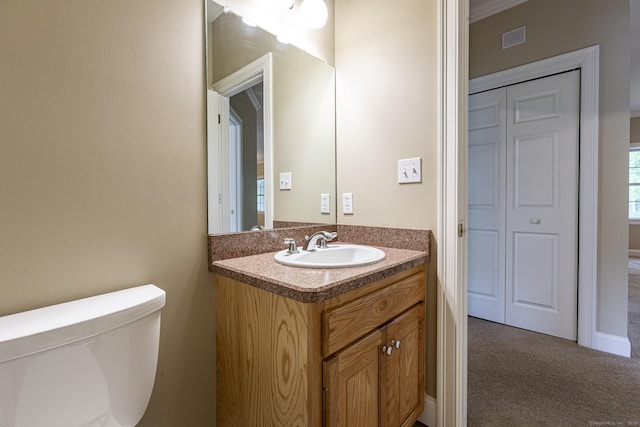 half bath with vanity, toilet, and visible vents