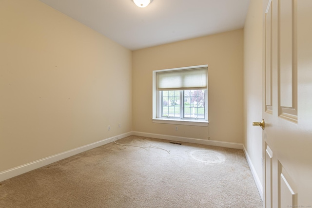 empty room featuring baseboards, visible vents, and light colored carpet