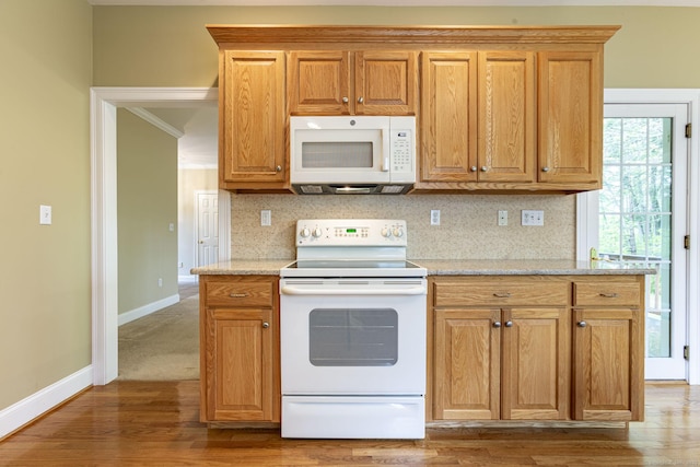 kitchen with white appliances, backsplash, light stone countertops, baseboards, and light wood-style floors