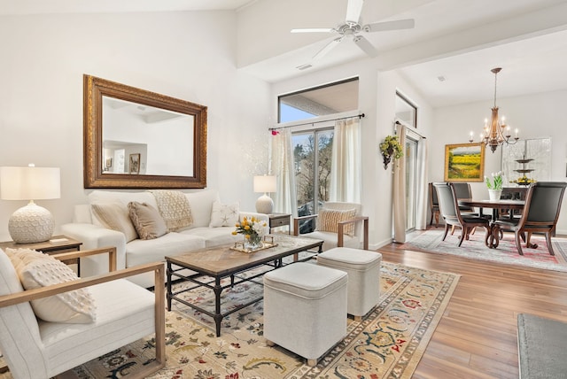 living room with high vaulted ceiling, ceiling fan with notable chandelier, and light hardwood / wood-style floors