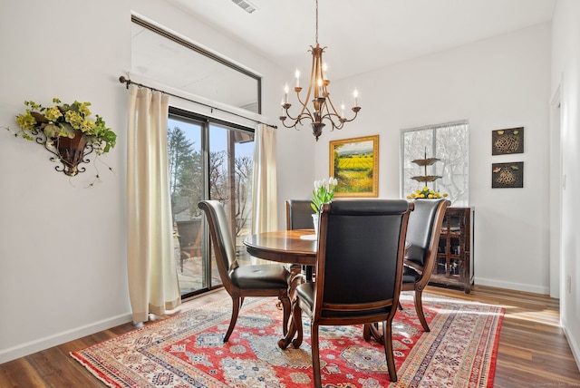 dining space featuring dark wood-type flooring and an inviting chandelier