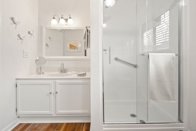 bathroom with hardwood / wood-style floors, a shower with door, and vanity